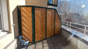 A covered outdoor seating area with a metal railing, a blue chair, and a view of a mountain in the background. - 2-room apartment night area, parking, wifi - Briançon (Briançon)