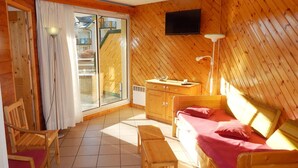 A wooden cabin room with a bed, a desk, a chair, a television, and a sliding glass door leading to a balcony. - 2-room apartment night area, parking, wifi - Briançon (Briançon)