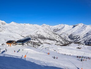A snow-covered ski slope with a building labeled 'Cote Chevalier' and a clear blue sky.