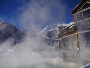 A building with large windows, a wooden exterior, and a view of snow-covered mountains.