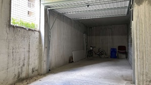 Un garaje con piso de concreto, una bicicleta y una silla.