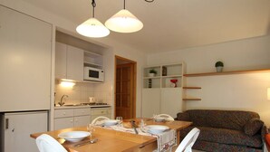 A compact kitchen with white cabinets, a microwave, and a dining table set for four.