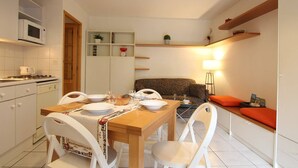 A compact kitchen with a dining table, chairs, a microwave, and a built-in oven.