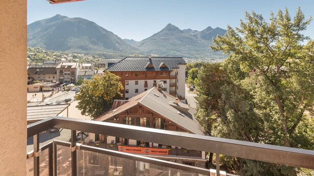 A hotel with a view of mountains, a parking area, and a Harley-Davidson sign. - Cozy studio 2/4 pers, Near Prorel lift and center (Briançon)