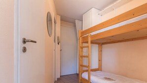A narrow hallway with a wooden bunk bed and a door with a round mirror and a light switch. - Cozy studio 2/4 pers, Near Prorel lift and center (Briançon)