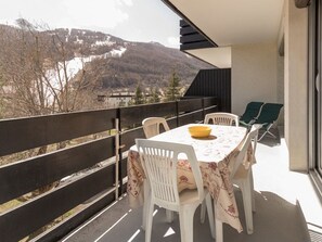 Un balcón con mesa y sillas, con vistas a un paisaje montañoso.