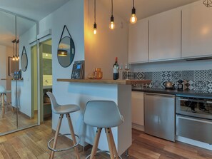 A modern kitchen with a bar area, stainless steel appliances, and a tiled backsplash.
