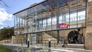 Un edificio moderno con grandes ventanales y un cartel que dice "GARE DE COURBEVOIE SNCF".