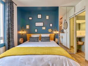 A bedroom with a bed, bedside tables, a wardrobe, and a bathroom visible through an open door.