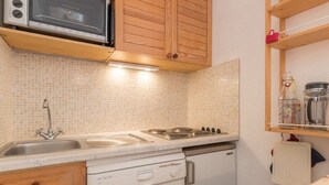 A compact kitchen with a microwave, stove, sink, and dishwasher. - Cozy mountain studio for 5 people in Chantemerle - Serres-Chevalier (Saint-Chaffrey)