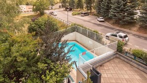 Una piscina con vistas a una carretera y bosque circundante.