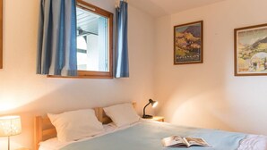 Un dormitorio con una cama, una mesita de noche, una lámpara y dos carteles en la pared.