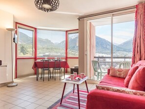 A room with a dining table and chairs, a sofa, and large windows offering a mountain view. - 2-room apartment with balcony, near slopes - Briançon (Briançon)