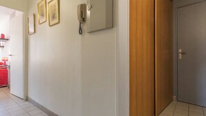 A hallway with a wooden door, a phone, and framed pictures on the wall. - 2-room apartment with balcony, near slopes - Briançon (Briançon)