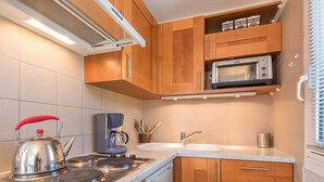 A compact kitchen with wooden cabinets, a built-in microwave, a kettle, and a coffee maker. - 2-room apartment with balcony, near slopes - Briançon (Briançon)