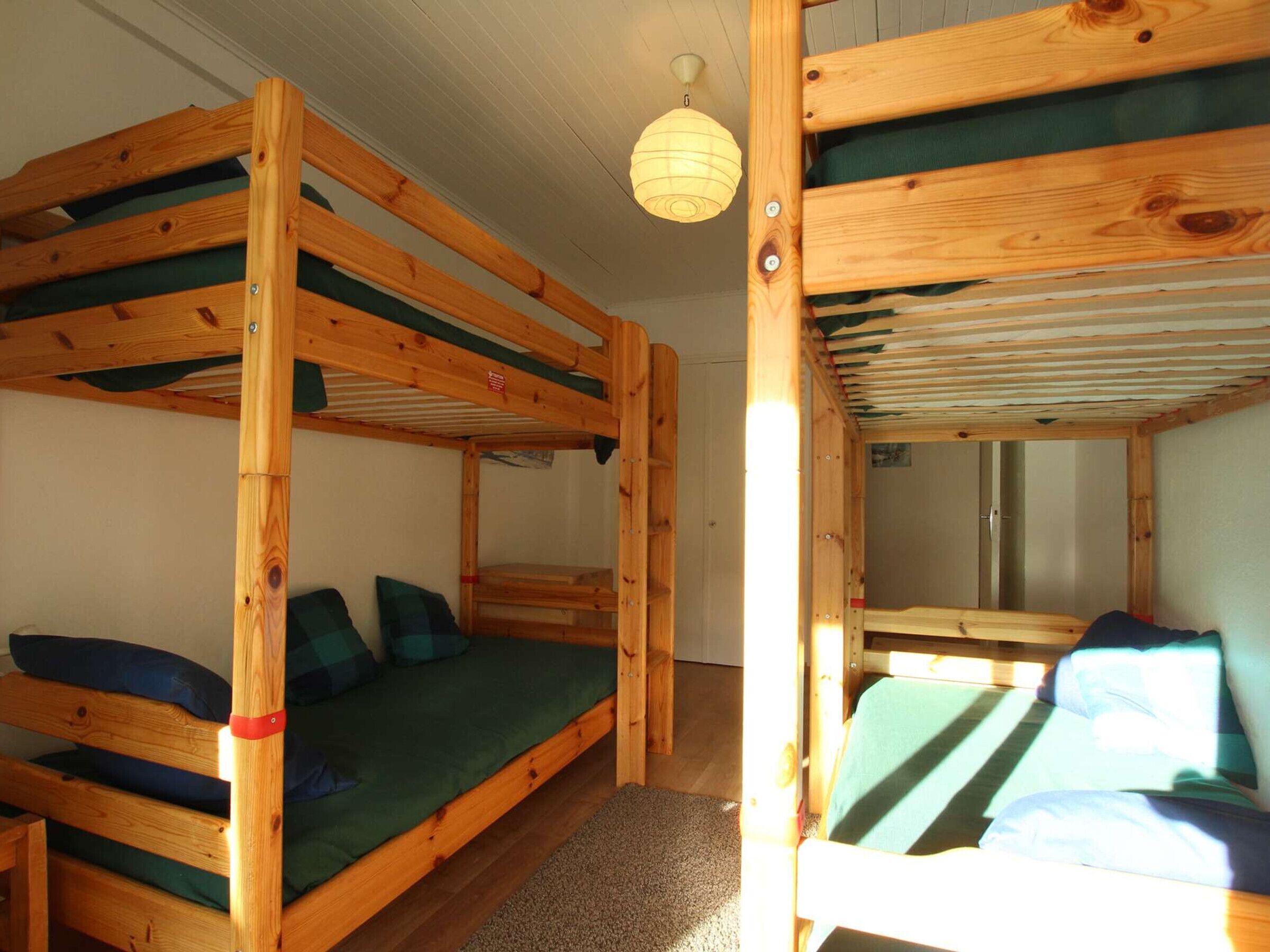 Dormitorio con literas de madera y ropa de cama verde.