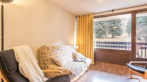 A cozy room with a sofa, a chair, and a large window with curtains.