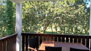 A wooden table and chairs on a covered patio with a view of trees. - Apartment in a residential leisure *** for 4 people (Moliets-Et-Maa)