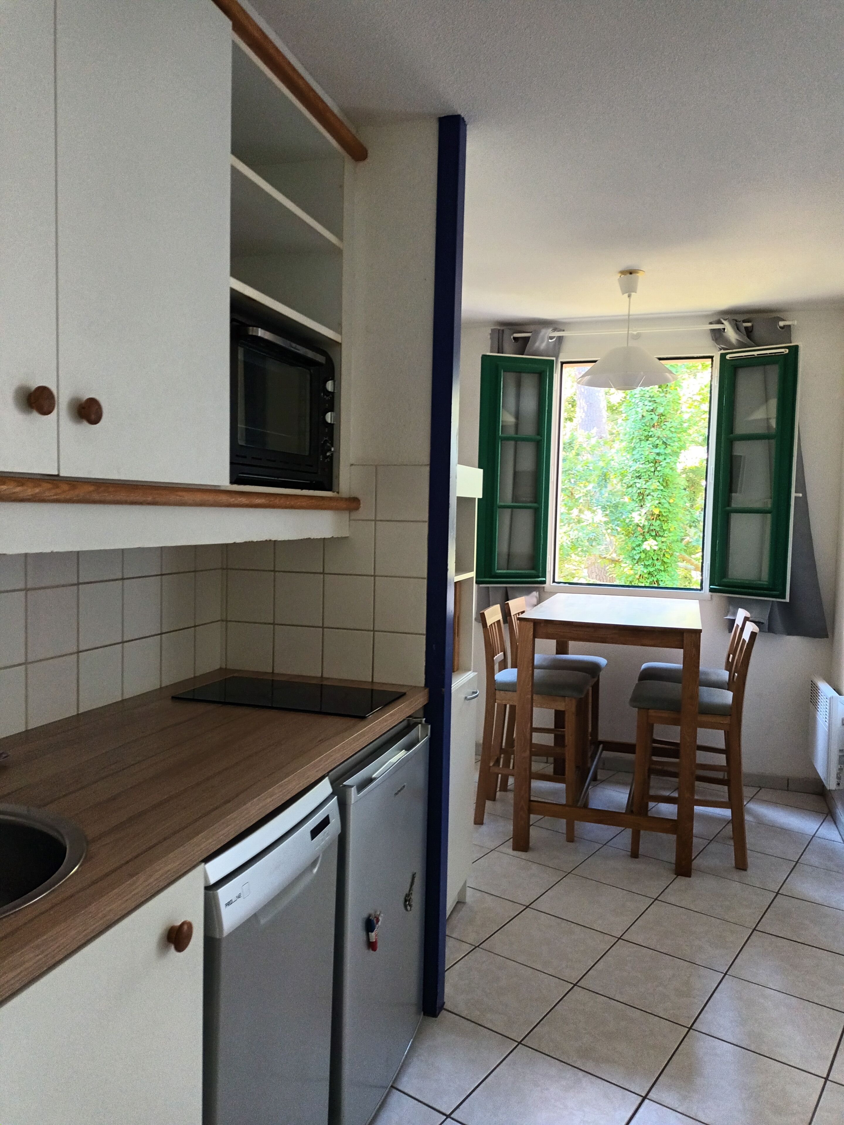 A compact kitchen with a microwave, dishwasher, and a small table with chairs.