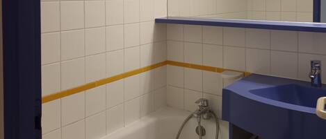 A bathroom with white tiled walls, a blue sink, and a bathtub.