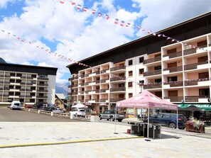 Un hotel de varios pisos con balcones, un estacionamiento y vistas a la montaña.