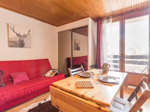 Una habitación acogedora con un sofá rojo, una mesa de madera con una bandeja y un ventanal con cortinas.