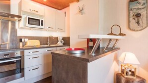 A modern kitchen with white cabinets, a microwave, a coffee machine, and a red bowl on the counter. - Renovated studio near slopes, parking, equipped kitchen (La Salle-les-Alpes)