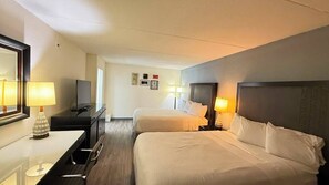 A hotel room with two beds, a desk, a chair, a TV, and a mirror.