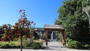 A pathway leading to a building with a wooden archway, surrounded by greenery and trees.