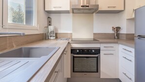 A modern kitchen with a stainless steel sink, a built-in oven, and a coffee maker.