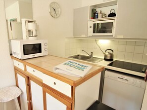 Une cuisine compacte équipée d’un four à micro-ondes, d’une bouilloire et d’un lave-vaisselle Bosch.