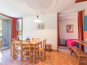Et spiseområde med et træbord, stole, en hængende lampe og en bænk.