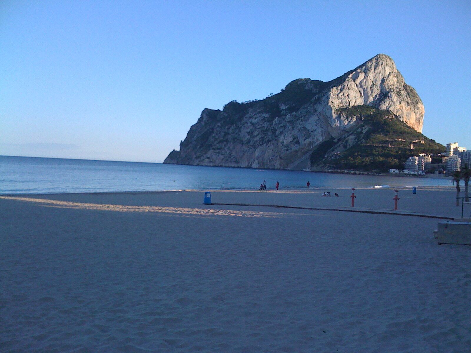 A beach with a large rock formation in the background.