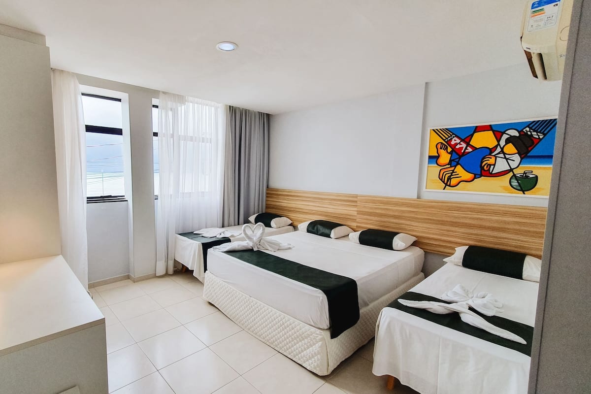 A hotel room with two beds, a desk, a TV, and a painting on the wall.
