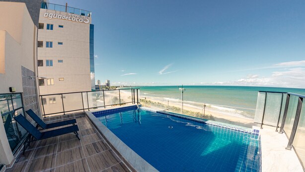 Ein Pool auf dem Dach mit Blick auf den Strand, ein Hotelgebäude und ein klarer Himmel.