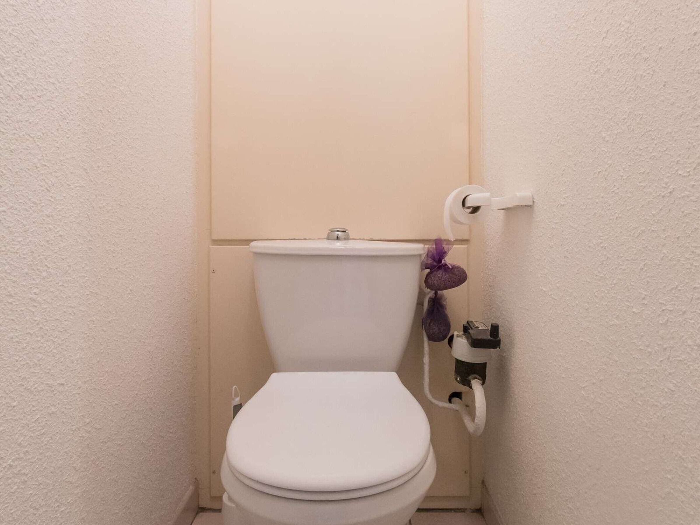 A small, white toilet with a plain wall and a door.