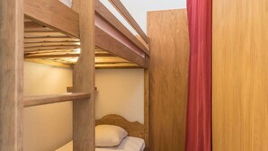 A bunk bed with a wooden frame and a single bed below.