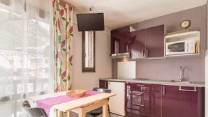 A compact kitchen with a dining area, featuring a table, chairs, a microwave, and cabinets.