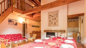 Un coin repas avec une nappe rouge, des meubles en bois et un escalier menant à une autre pièce.