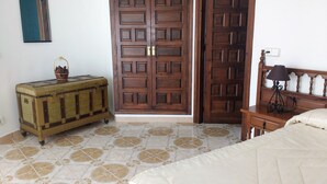 A bedroom with a bed, a wooden dresser, a nightstand with a lamp, and a large wooden door. - Detached villa for 6 people located in Miami Playa (MIAMI PLAYA)