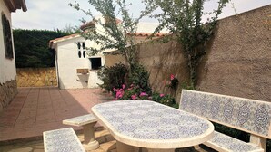 A patio area with a tiled table and benches, surrounded by a stone wall and a small building with a window. - Detached villa for 6 people located in Miami Playa (MIAMI PLAYA)