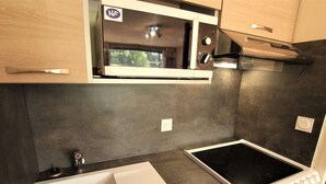 A compact kitchen with a built-in microwave, a stovetop, and a sink. - Cozy Mountain Studio for 4 with Ski-In Access and Seasonal Pool (La Salle-les-Alpes)