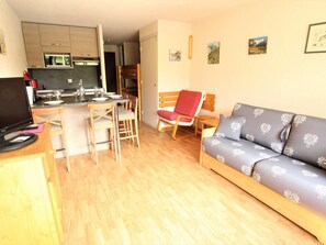 Un espacio habitable compacto con kitchenette, comedor y sofá.