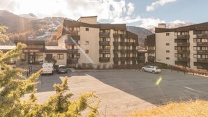 A multi-story hotel with a parking lot, surrounded by mountains and trees.