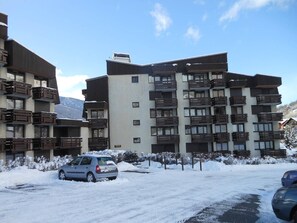 Een meerlaags hotel met balkons, een parkeerplaats en een besneeuwde omgeving.