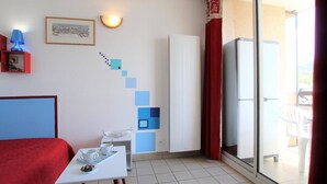 A room with a bed, a table with cups and a plate, a picture on the wall, a staircase, and a sliding glass door leading to an outdoor area.