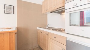 A compact kitchen with wooden cabinets, a built-in oven, and a microwave.