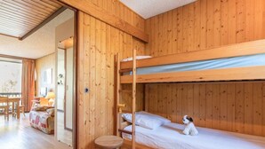 Een houten kamer met een stapelbed, een klein tafeltje en een stoel.