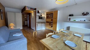 Een compacte leefruimte met een eethoek, kitchenette en een gezellige zithoek.