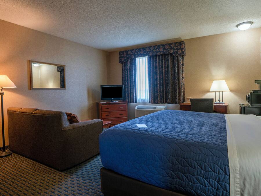 Une chambre d’hôtel équipée d’un lit, d’un bureau, d’une chaise, d’une télévision et d’une lampe de bureau.